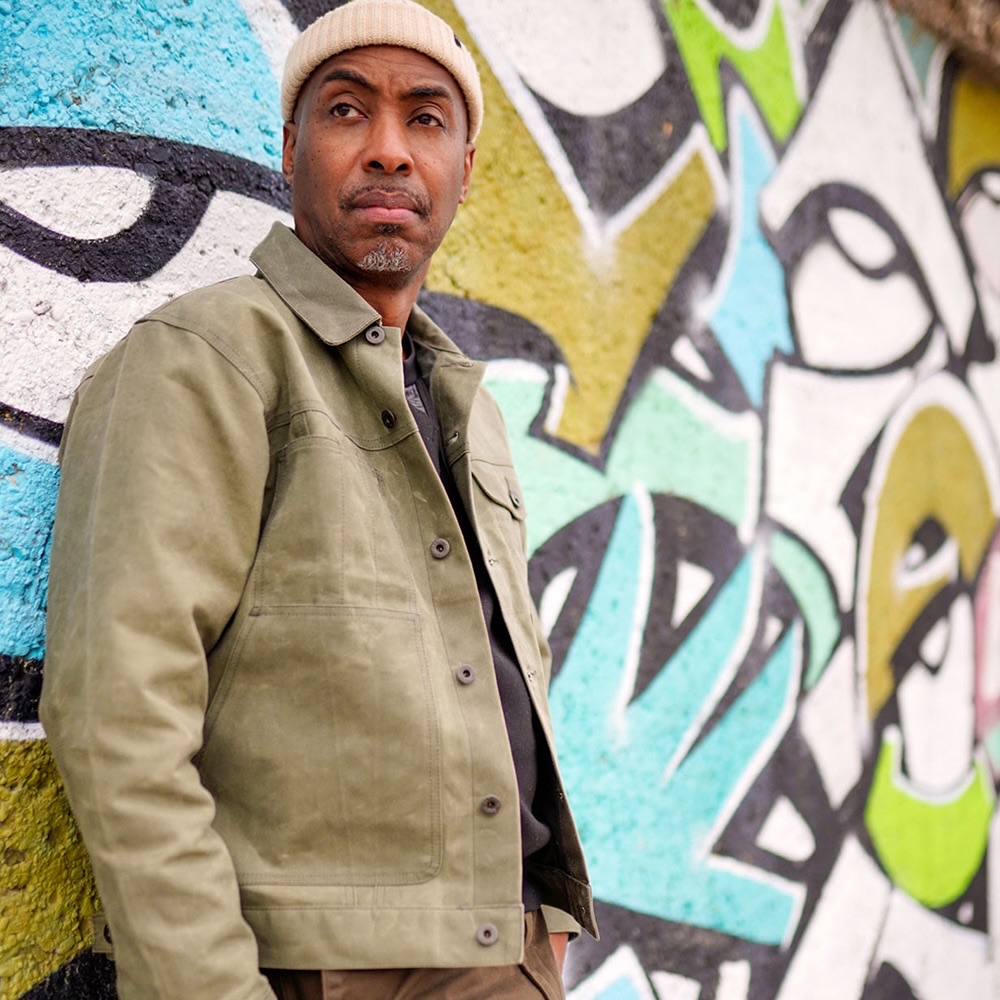 Mic Fox, founder and host of rapfabulous, standing in front of a graffiti wall